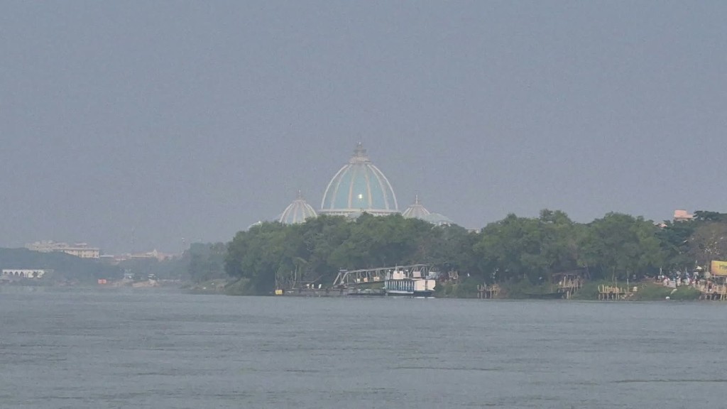 White domed temple across the river through morning mist